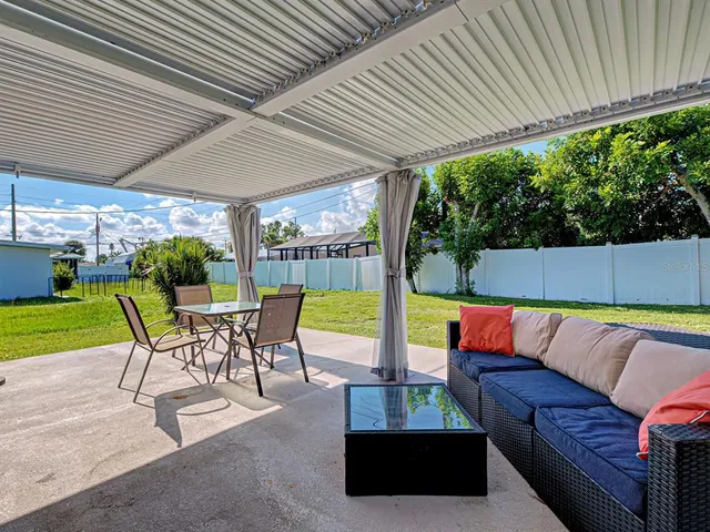 a view of a patio with couches table and chairs under an umbrella