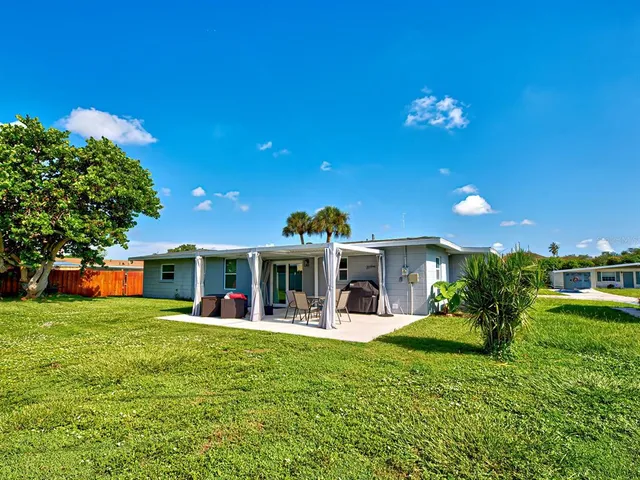a view of a house with a big yard potted plants and a large tree