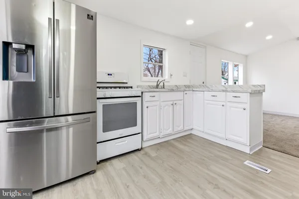 a kitchen with stainless steel appliances white cabinets and wooden floors