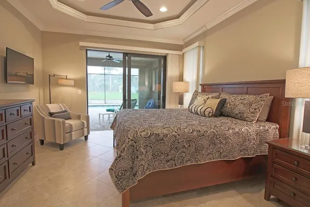 a bed sitting in a bedroom next to a window with a tv and a dresser