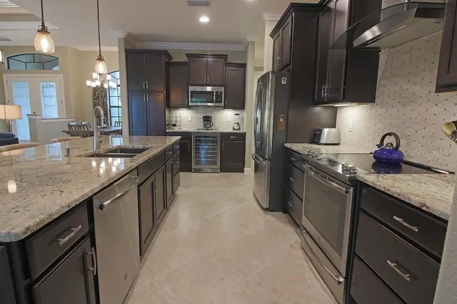 a kitchen with stainless steel appliances granite countertop sink stove refrigerator and cabinets