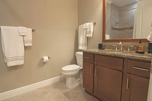 a bathroom with a granite countertop toilet sink and mirror