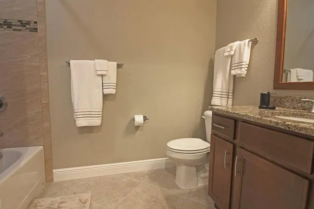 a bathroom with a granite countertop toilet and a sink