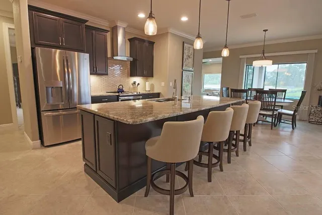 a kitchen with stainless steel appliances granite countertop a stove a refrigerator a kitchen island a dining table and chairs