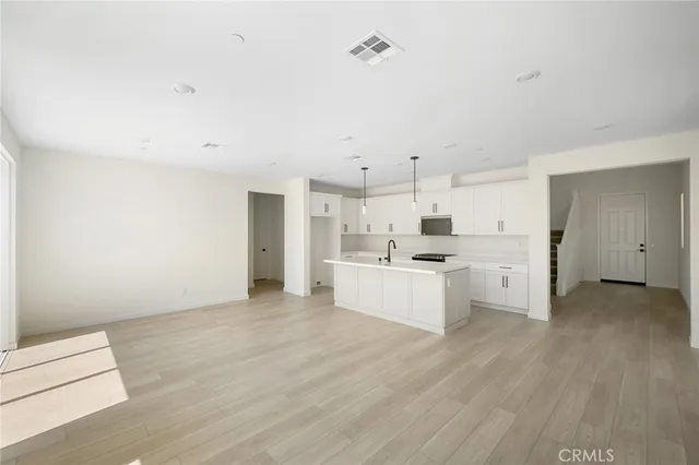 a large white kitchen with white cabinets sink and stainless steel appliances