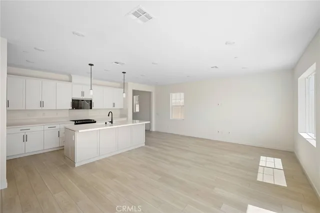 a large white kitchen with cabinets wooden floor and a sink
