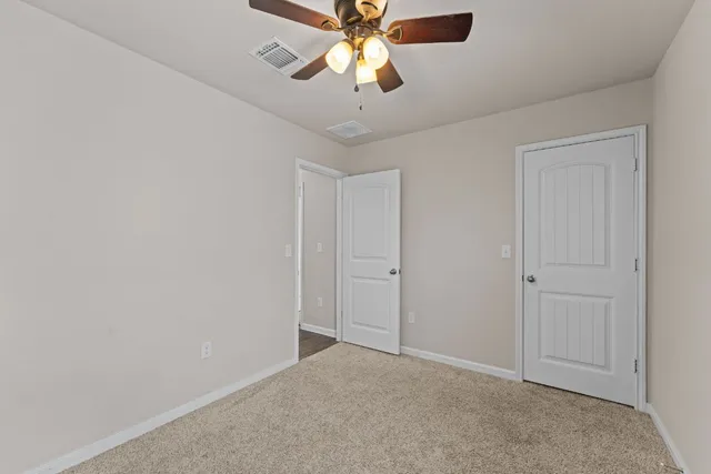 a view of an empty room and chandelier fan