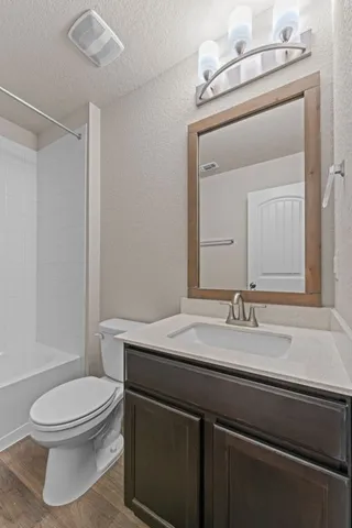 a bathroom with a granite countertop toilet sink mirror and vanity
