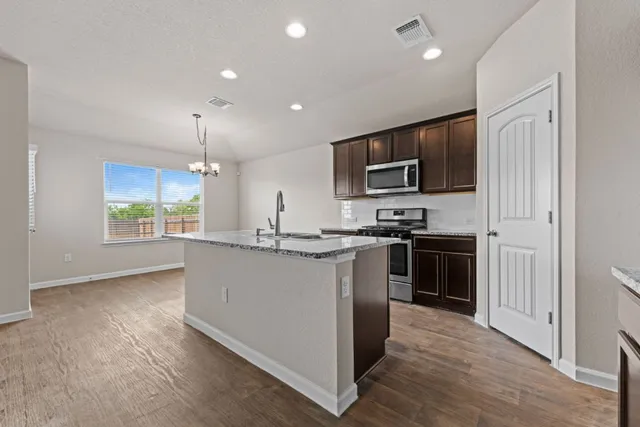 a kitchen with kitchen island granite countertop stainless steel appliances stove microwave and cabinets