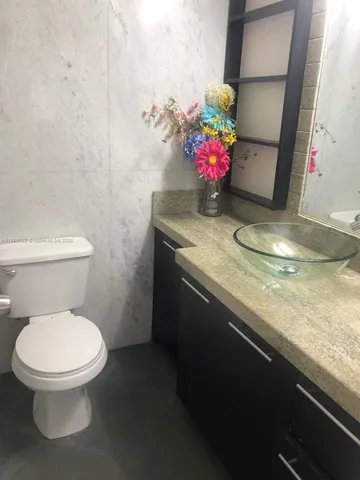 a bathroom with a granite countertop sink a toilet and a mirror