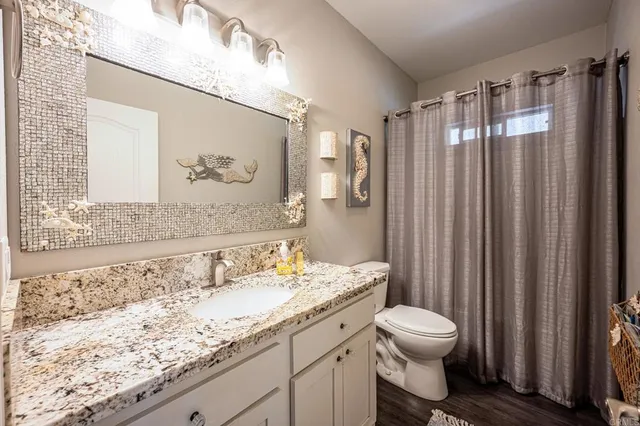 a bathroom with a granite countertop sink a toilet and a shower