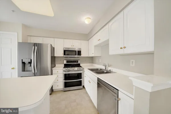a kitchen with stainless steel appliances a refrigerator stove microwave and white cabinets
