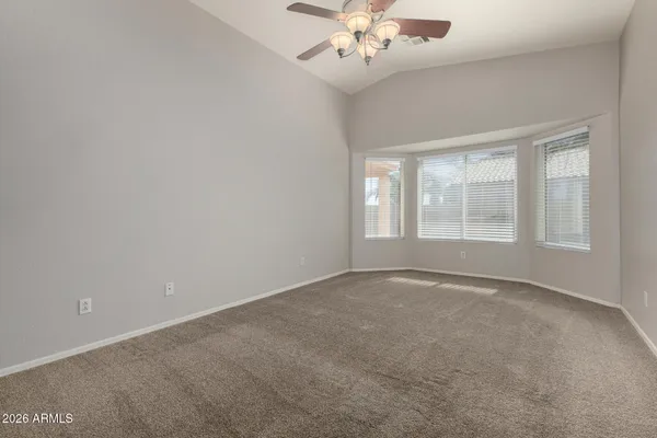 an empty room with a chandelier fan and windows