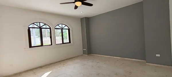 an empty room with windows and ceiling fan