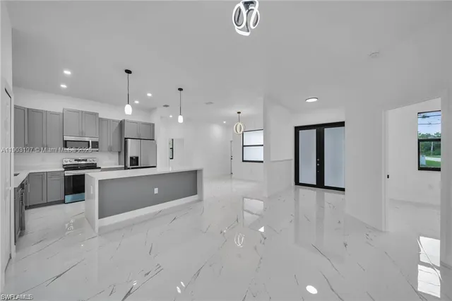 a large kitchen with stainless steel appliances kitchen island a white counter space a sink and a refrigerator