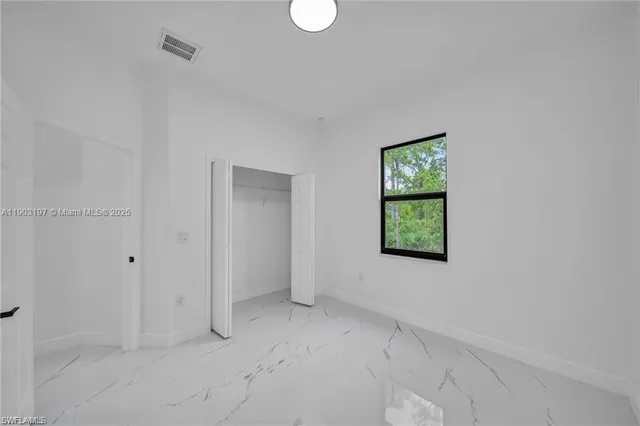 a view of an empty room with window and closet area