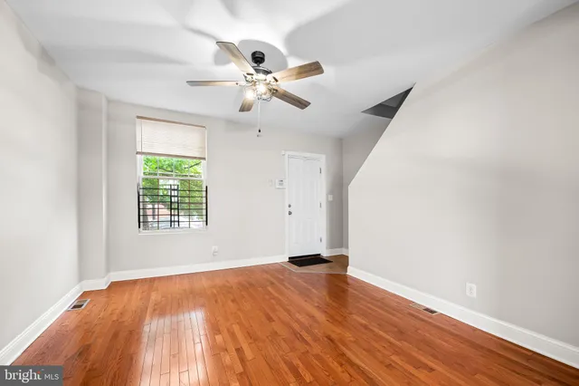 a view of an empty room with wooden floor and a window