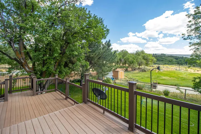 a view of a balcony with wooden floor next to a yard