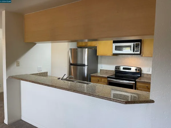 a kitchen with granite countertop a refrigerator and a stove top oven