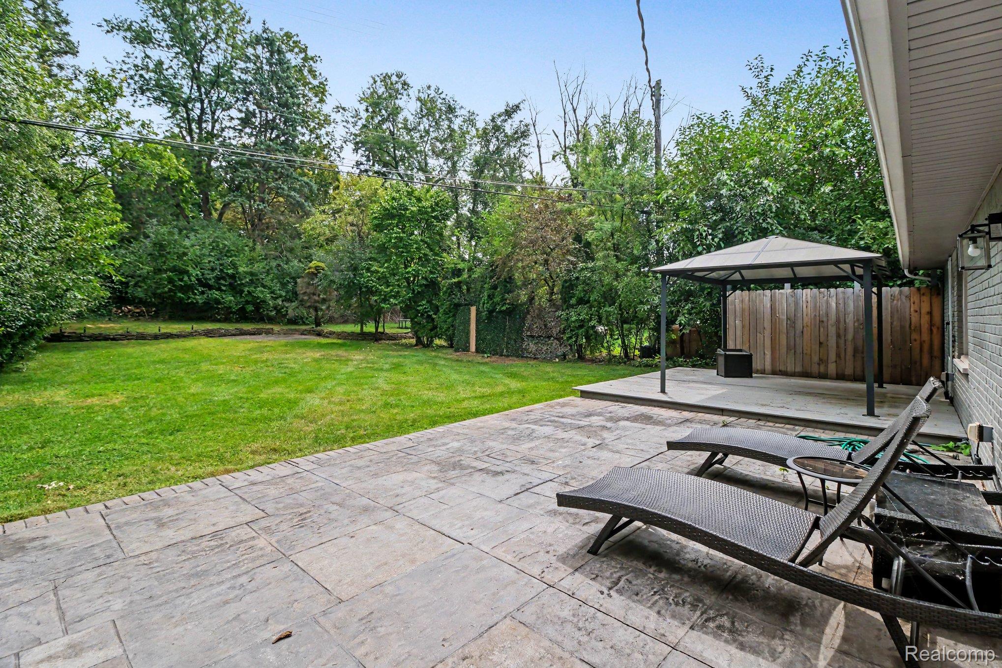 2373 Rutherford Road Bloomfield Hills, MI 48302 - Photo 23 of 28 Expansive backyard featuring a large grass area, a patio with stamped concrete, a raised deck area, and a permanent gazebo structure