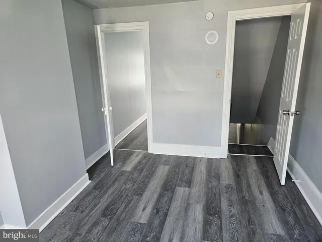 an empty room with wooden floor and entrance
