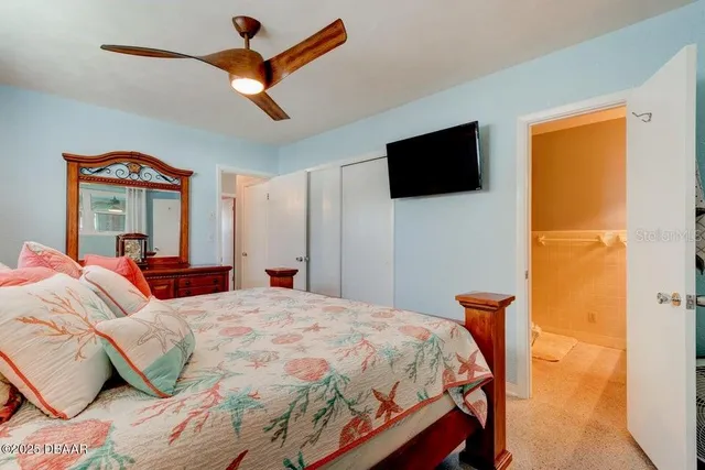 a bedroom with a bed and a flat tv screen on the dresser