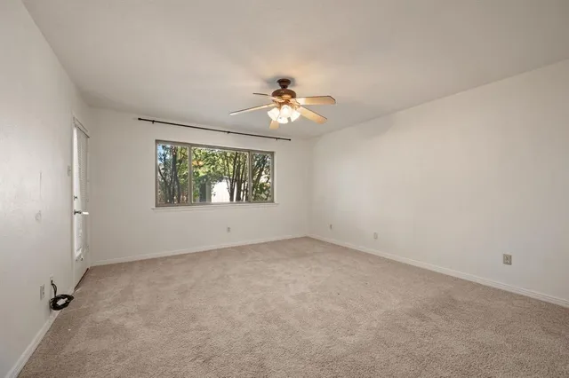 an empty room with windows and ceiling fan