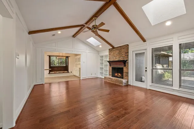 a view of an empty room with wooden floor fireplace and a window
