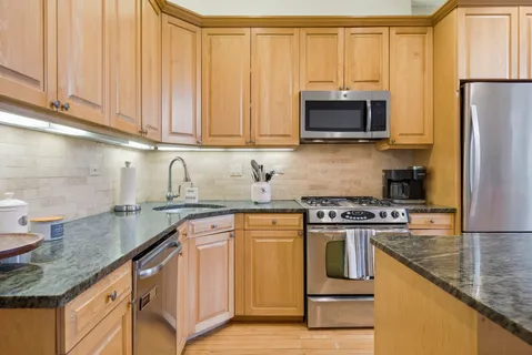a kitchen with granite countertop a sink stove and refrigerator