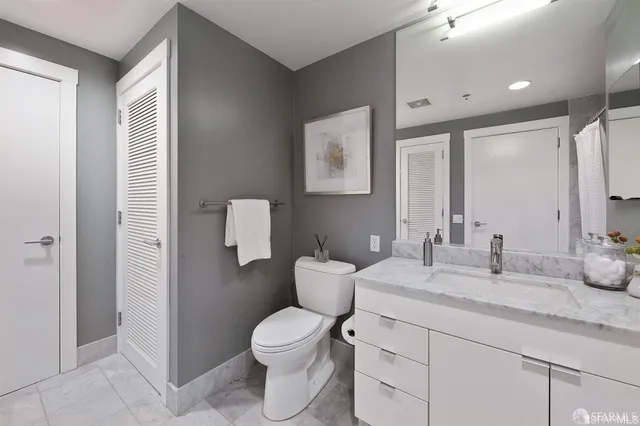 a bathroom with a granite countertop toilet sink and mirror