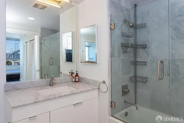 a bathroom with a granite countertop sink a mirror and shower