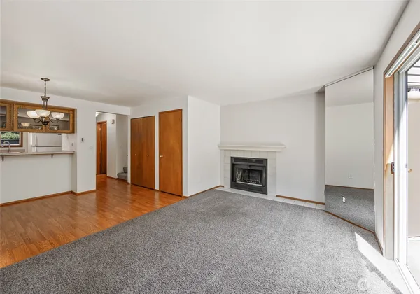 an empty room with wooden floor fireplace and windows