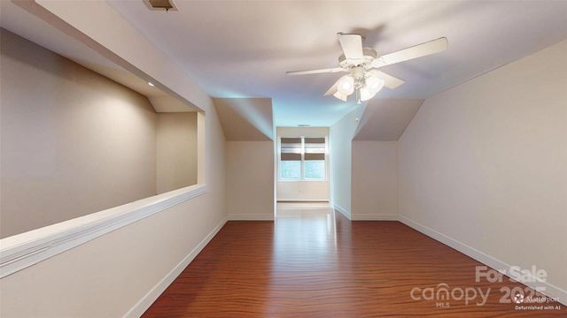 a view of an empty room with wooden floor and a ceiling fan
