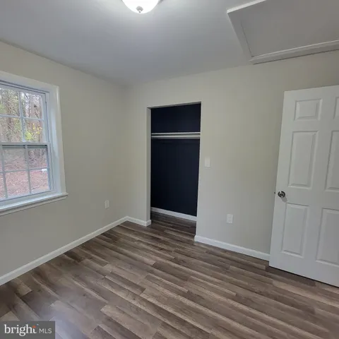 a view of an empty room with wooden floor and closet