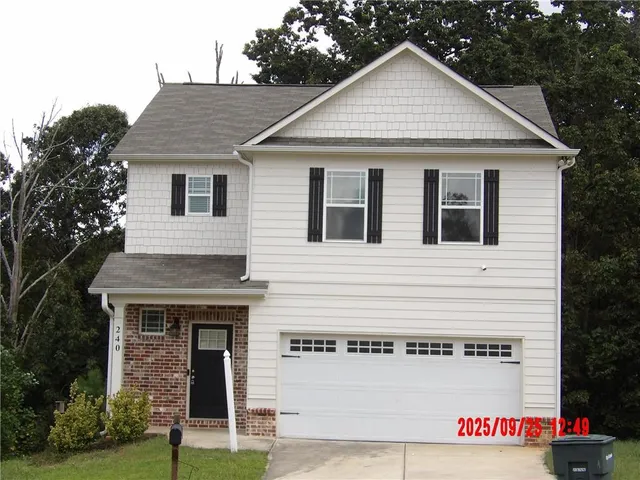 a view of a white house with large windows and a small yard