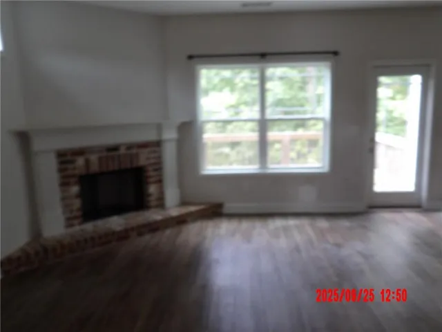 an empty room with wooden floor fireplace and windows