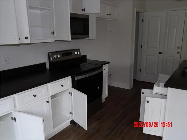 a kitchen with white cabinets and black appliances