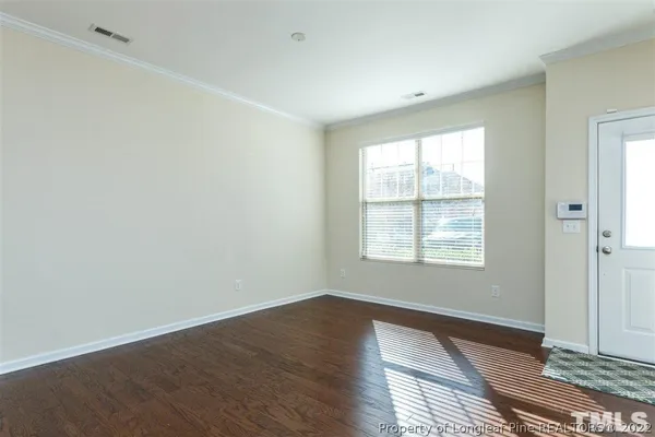 a view of an empty room with wooden floor and a window