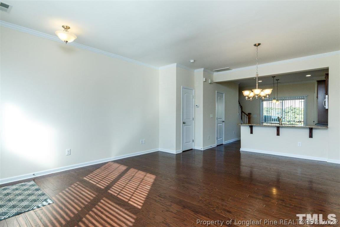 110 Mt Evans Drive Durham, NC 27705 - Photo 7 of 27 a view of an empty room with wooden floor and a kitchen