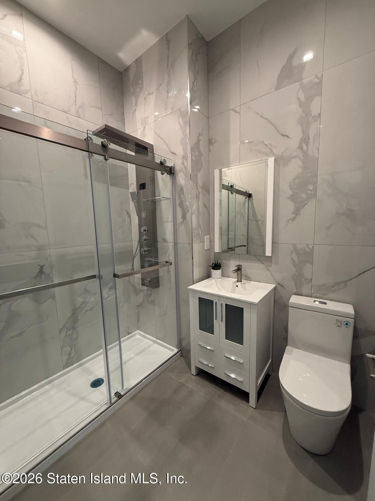 1239 Forest Hill Road, Unit 21 Staten Island, NY 10314 - Photo 14 of 15 a bathroom with a sink a toilet and a mirror