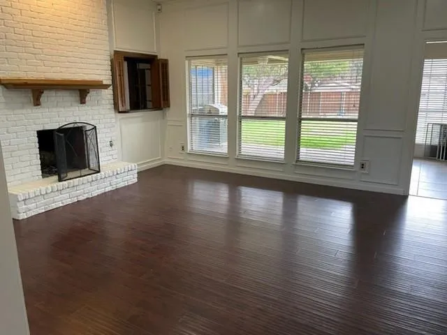 a view of a livingroom with wooden floor a fireplace and window