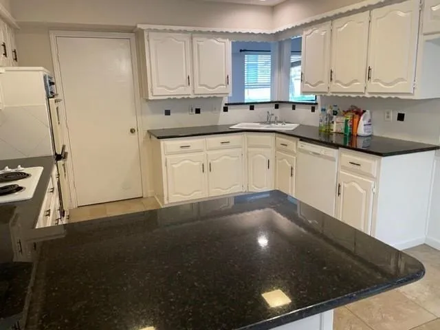 a kitchen with granite countertop white cabinets and white appliances
