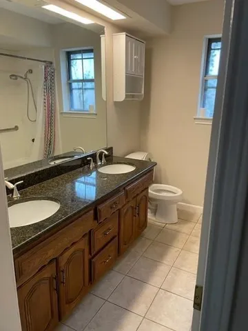 a bathroom with a granite countertop sink toilet and mirror