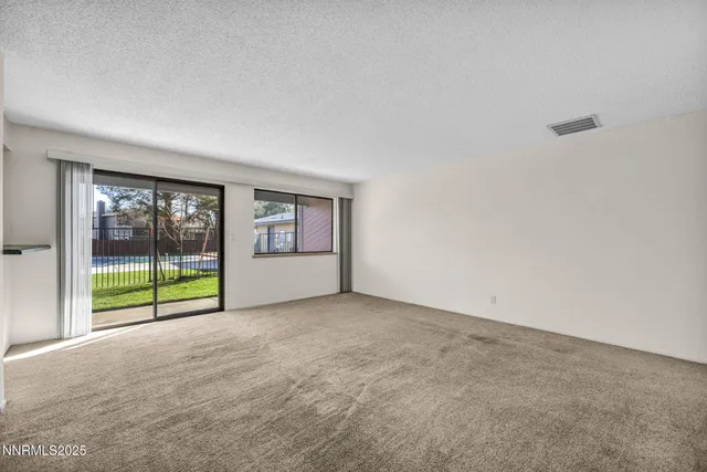 an empty room with floor to ceiling window and an outdoor view