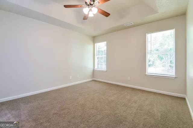 an empty room with windows and chandelier fan