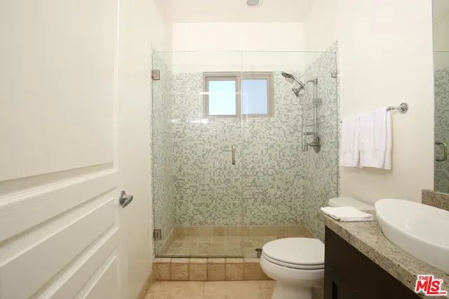 a bathroom with a granite countertop toilet a sink and a shower