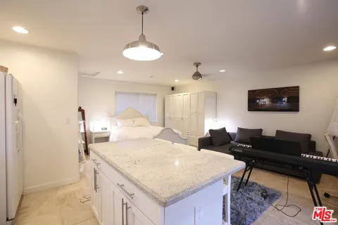 a large white kitchen with a stove a sink a refrigerator and a dining table with wooden floor