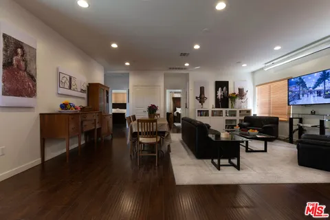 a living room with furniture kitchen view and a wooden floor