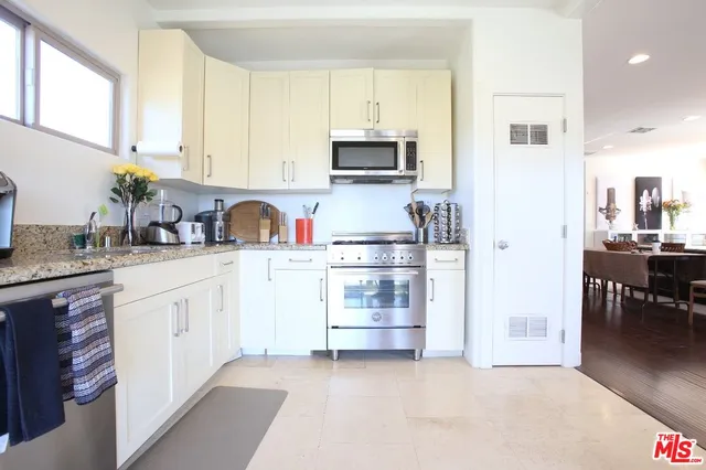 a kitchen with stainless steel appliances granite countertop a refrigerator and a stove top oven