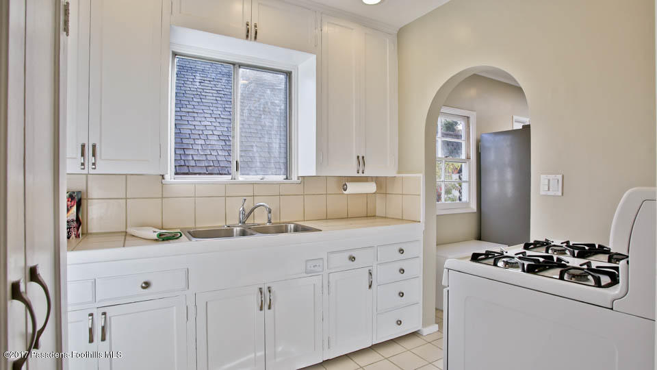 330 Fillmore Street Pasadena, CA 91106 - Photo 14 of 25 a kitchen with white cabinets a sink stainless steel appliances and a window